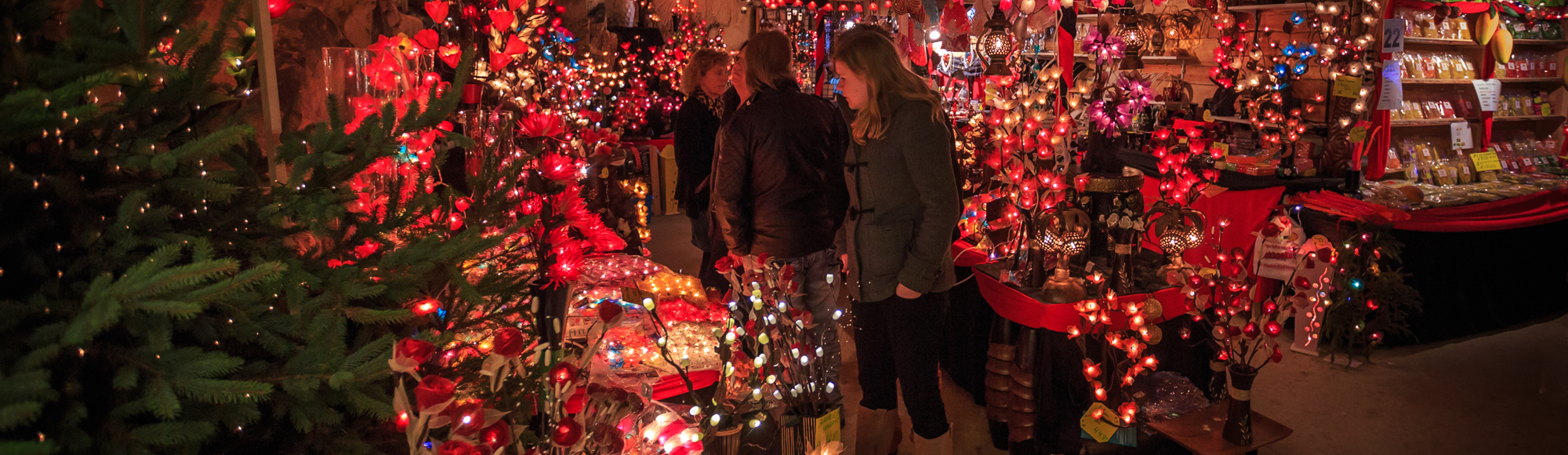 Mensen bekijken rode kerstversiering bij stand in Gemeentegrot