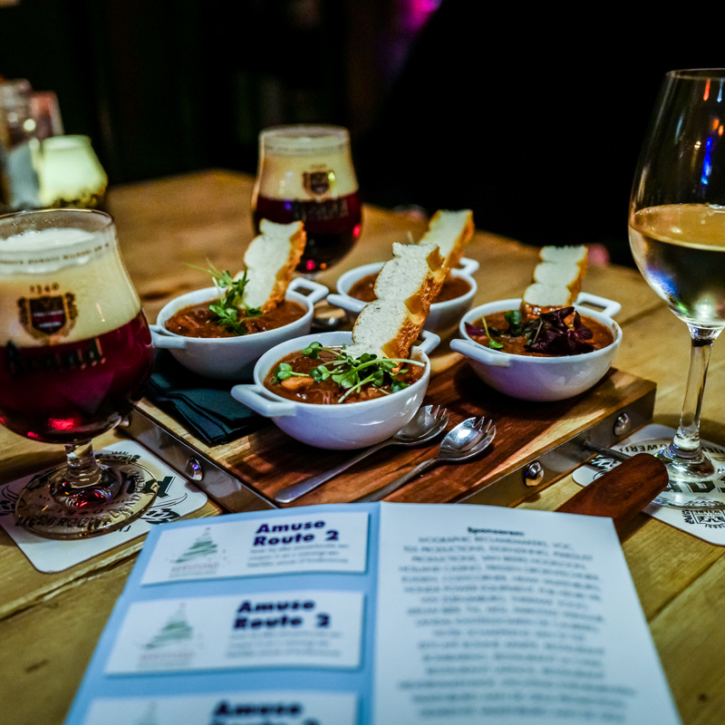 Houten tafel met 4 hapjes te midden van wijn en bier