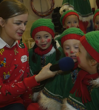 Presentatrice interviewt als kerstelfjes verklede kinderen
