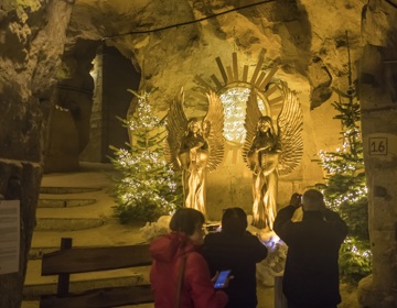 Oudere mensen fotograferen verlichte engelen in kerstmarkt Fluweelengrot