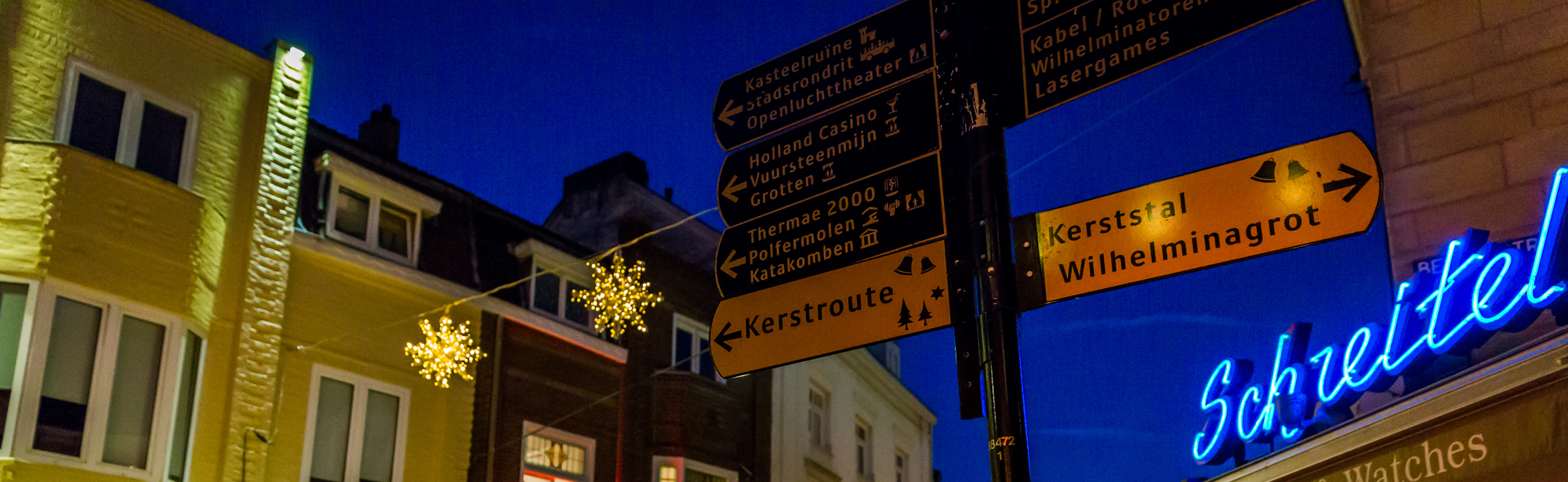 Wegwijzer op hoek van straat bij terrassen in Valkenburg