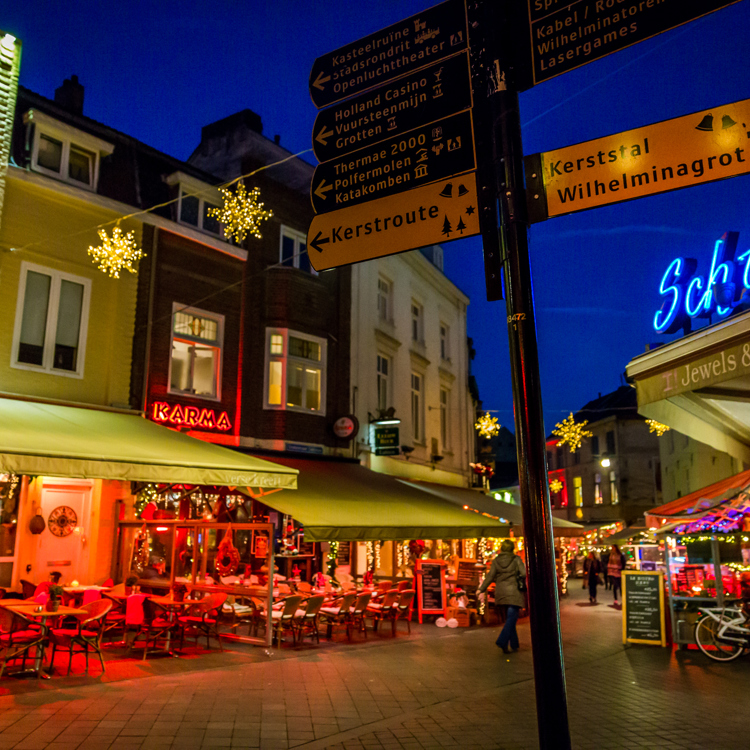 Wegwijzer op hoek van straat bij terrassen in Valkenburg