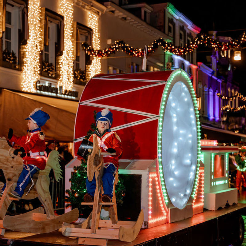 2 jongetjes in schutterspakjes op houten hobbelpaard op praalwagen in de Parade tijdens Kerststad Valkenburg