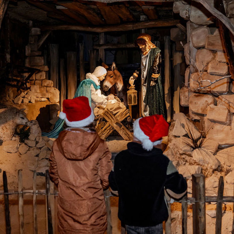 twee kinderen met kerstmutsen op kijken naar een levensgrote kerststal bij Winter Wonderland  in Kerststad Valkenburg